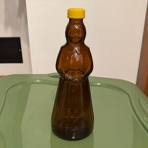 Vintage Mrs. Butterworth's amber brown glass syrup bottle with a yellow lid.